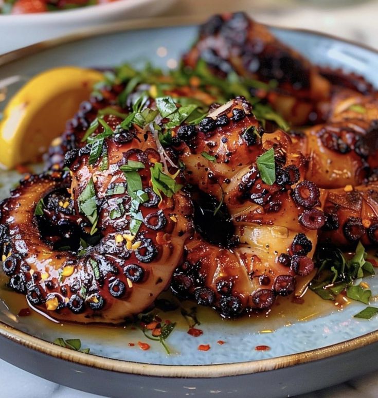 grilled octopus on a blue plate with lemon wedges and garnishes