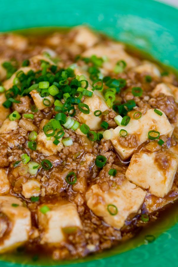 a green plate topped with tofu and onions