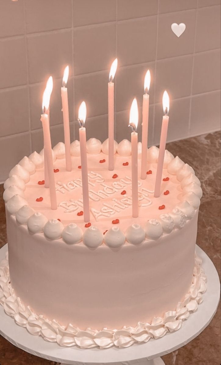 a birthday cake with lit candles on it in the shape of a heart and hearts