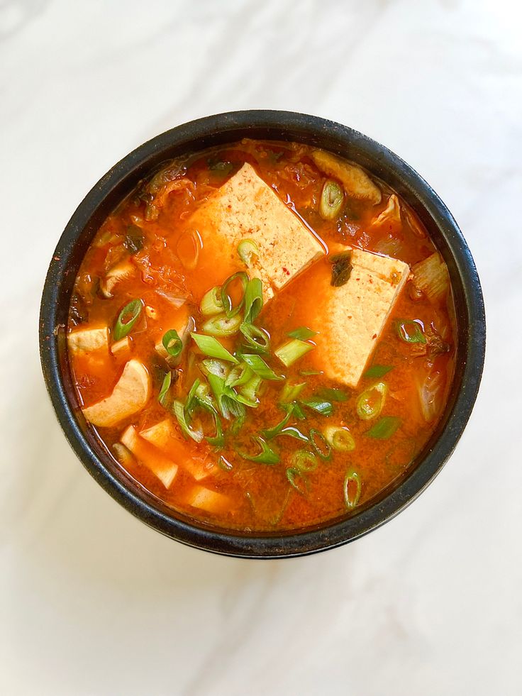 a bowl of soup with tofu and green onions