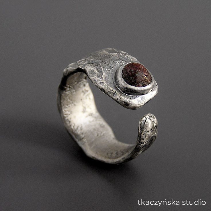 "Raw Organic Garnet Ring, Rough Natural Garnet Modern Ring, Contemporary Garnet Open Ring, Brutalist Raw Garnet Ring, Raw Spirit Collection Organic style uneven ring with raw garnet.  The fused and hammered band is black patinated and brushed. Made to order. The ring can be custom-made in any size, also with a different stone.  Due to the fact that each piece is made by hand with a unique stone, it can slightly vary from the one in the photos.  Each movement of a hand holding a torch, each blow of a hammer is a bit different and one of a kind. Because of that, the ring will be very similar but not identical.  Please check out the detailed size charts for S, M, and L sizes in the last photos. The ring in the photos is size: The ring in the photos is size: Europe 29, Great Britain Z, USA 12 Modern Garnet Ring, Wide Wedding Rings, Raw Garnet, Avant Garde Jewelry, Fantasy Ring, Unique Mens Rings, Silversmith Jewellery, January Birthstone Rings, Rough Jewelry