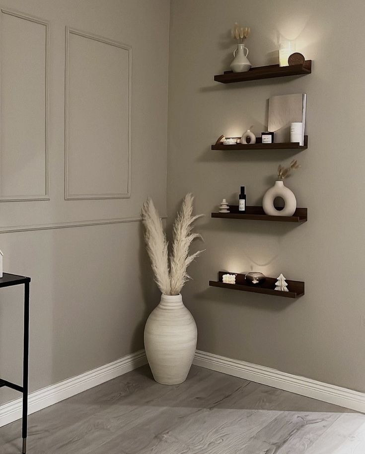 a white vase sitting on top of a wooden floor next to shelves filled with candles