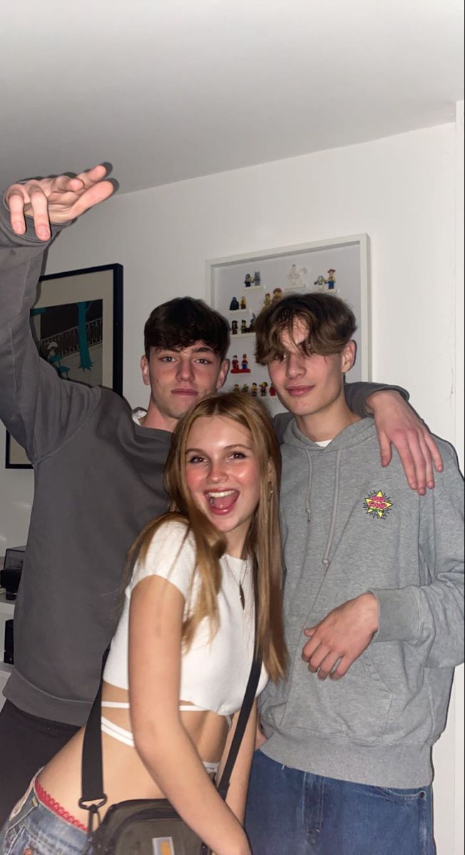 three young people posing for the camera in a room with white walls and flooring