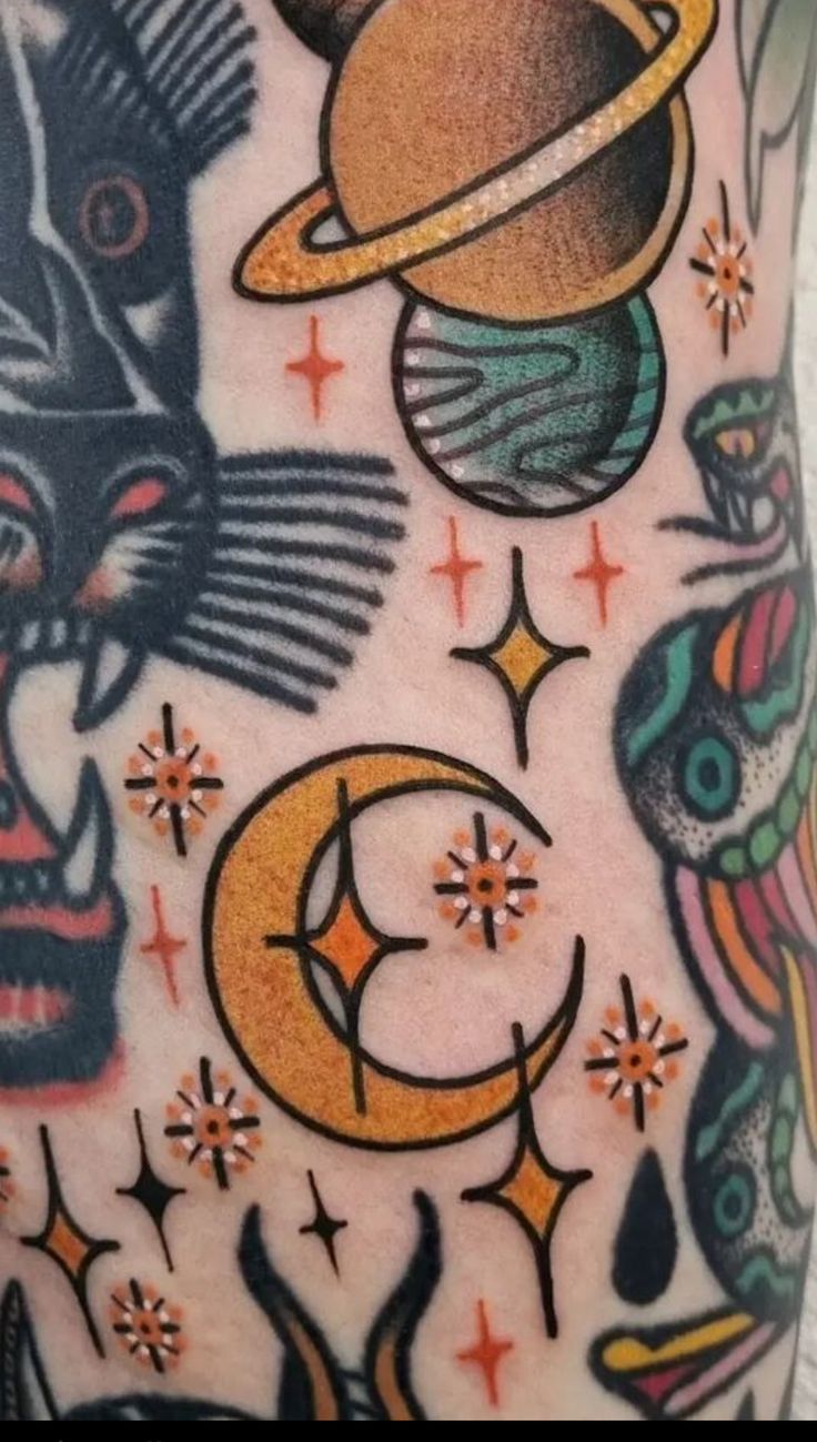 an arm with tattoos on it that include cats, saturn, and the moon in different colors