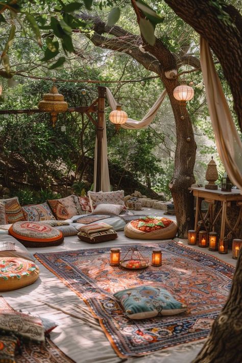 an outdoor seating area with pillows and candles on the ground, surrounded by tree branches