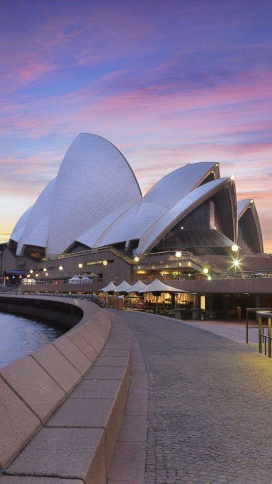 the sydney opera house is lit up at night