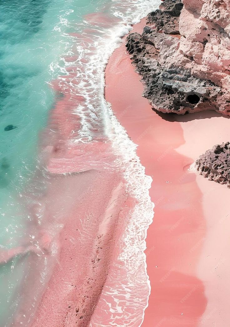 an aerial view of pink sand and water at the beach