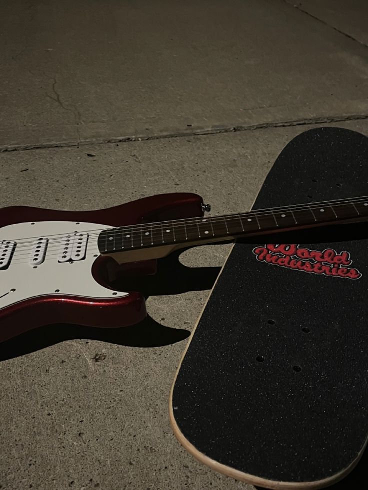 an electric guitar laying on the ground next to a skateboard