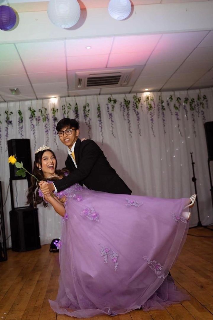 a man and woman posing for a photo on the dance floor with flowers in front of them