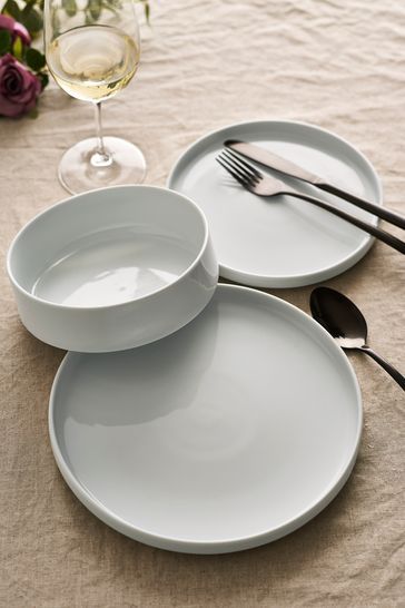 three empty plates and two wine glasses on a table