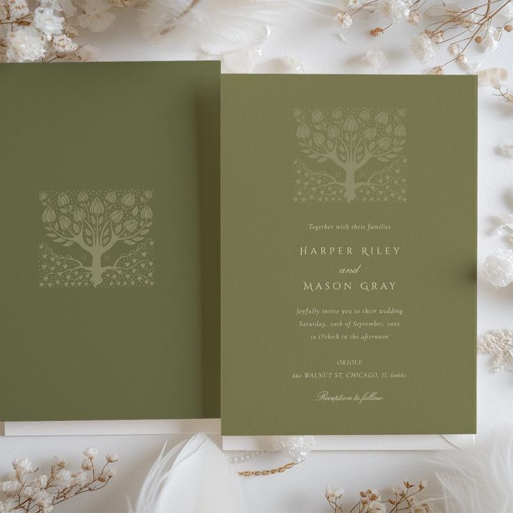 two green wedding cards sitting next to each other on top of a white flowery table