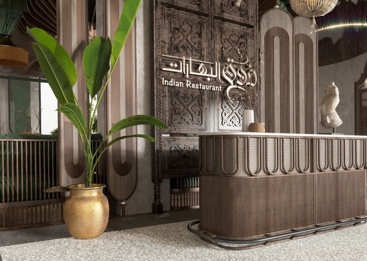 a large plant in a gold vase sitting next to a counter with an arabic writing on it