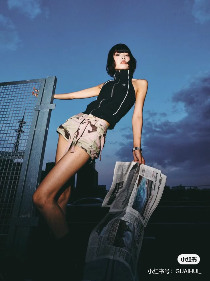 a woman leaning against a fence with her leg on the wall and magazine in front of her