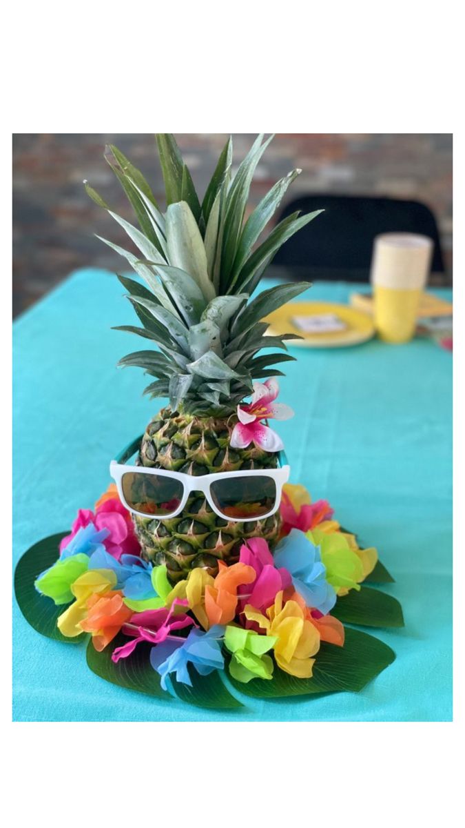 a pineapple with sunglasses on top of it sitting on a blue cloth covered table