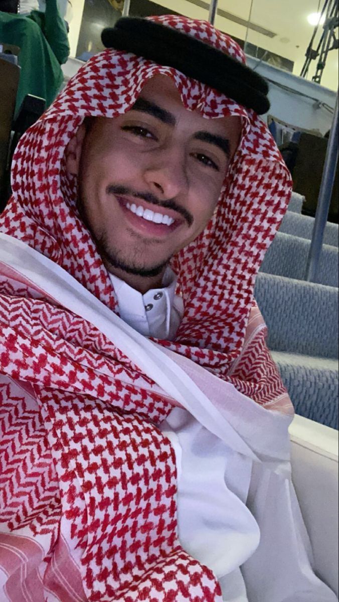 a man wearing a red and white checkered blanket on his head is smiling at the camera