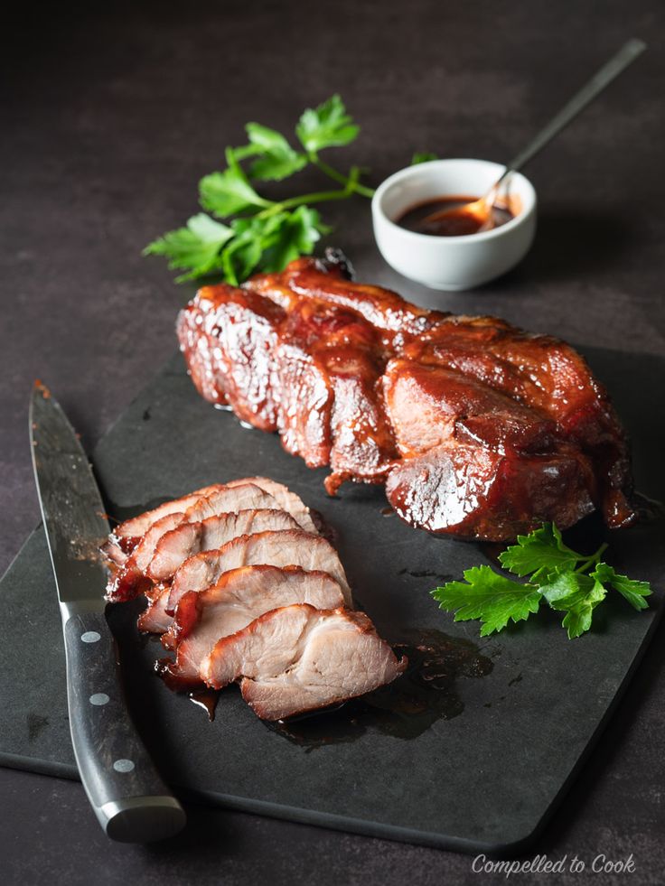 sliced meat on cutting board with knife and sauce