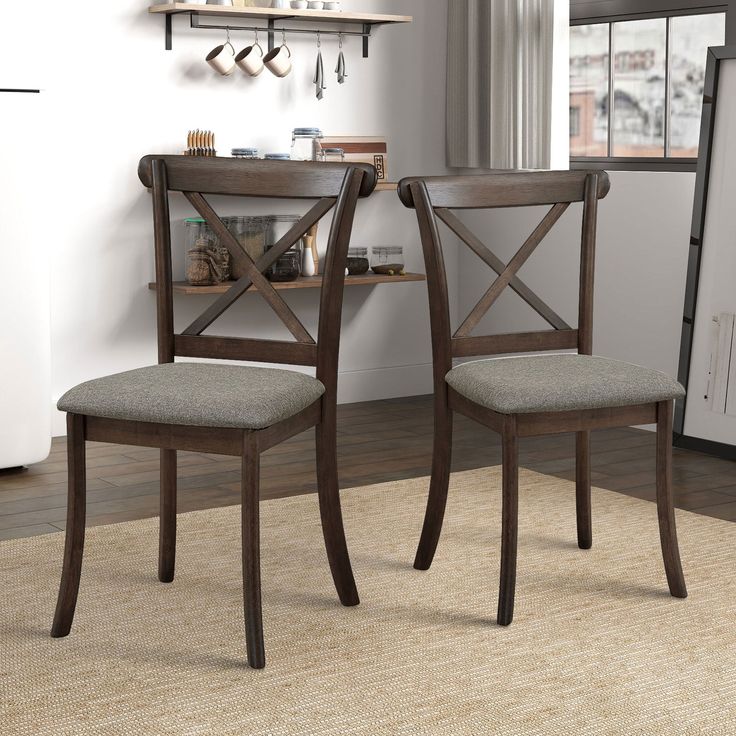 two wooden chairs sitting next to each other in a room with a rug on the floor