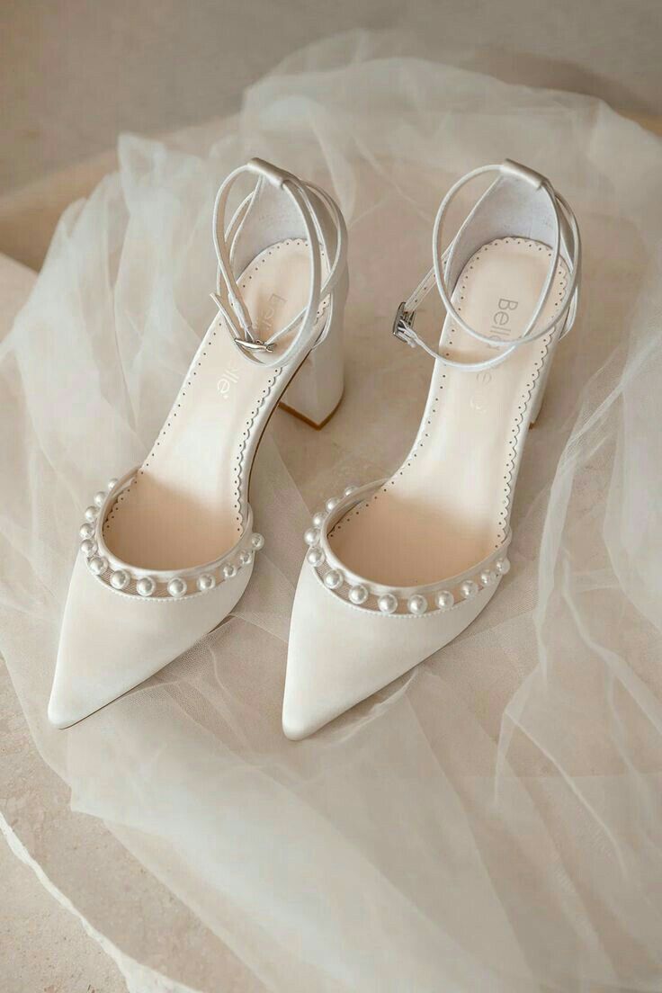 a pair of white shoes with pearls on them