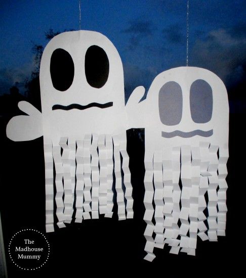 two paper cut out ghost decorations hanging on a window with the sky in the background