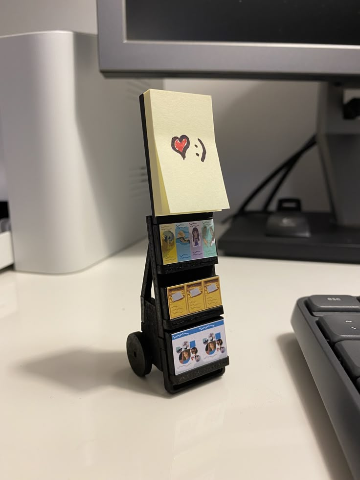 a small carton with cards attached to it sitting on a desk next to a keyboard