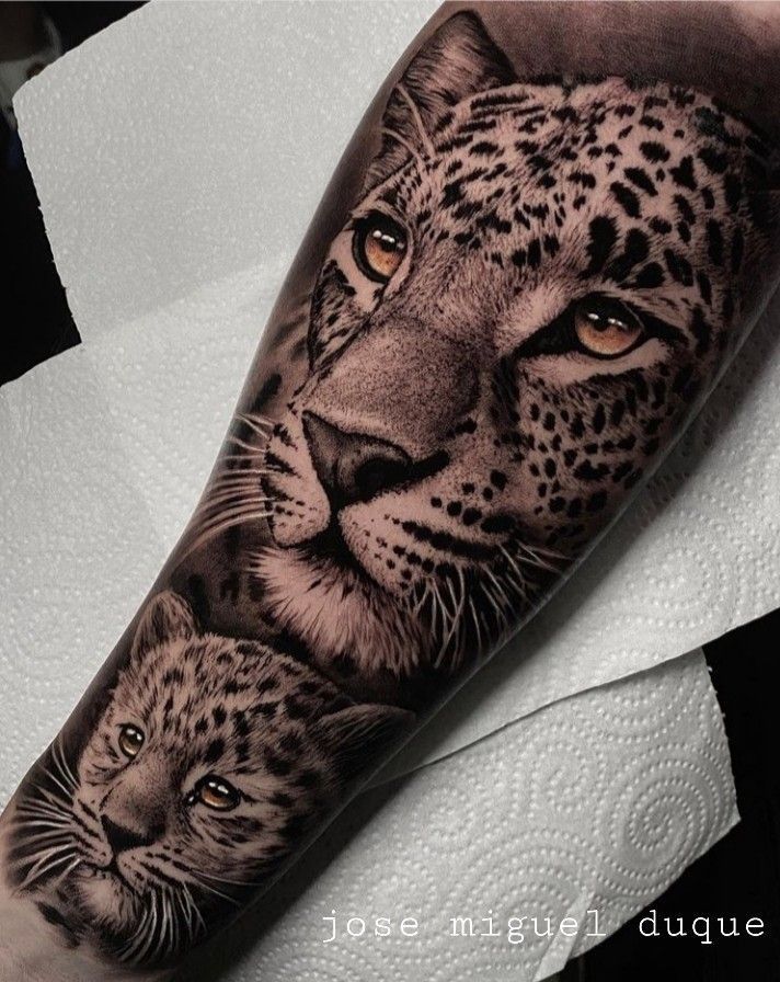 an arm tattoo with a cheetah and cub on it