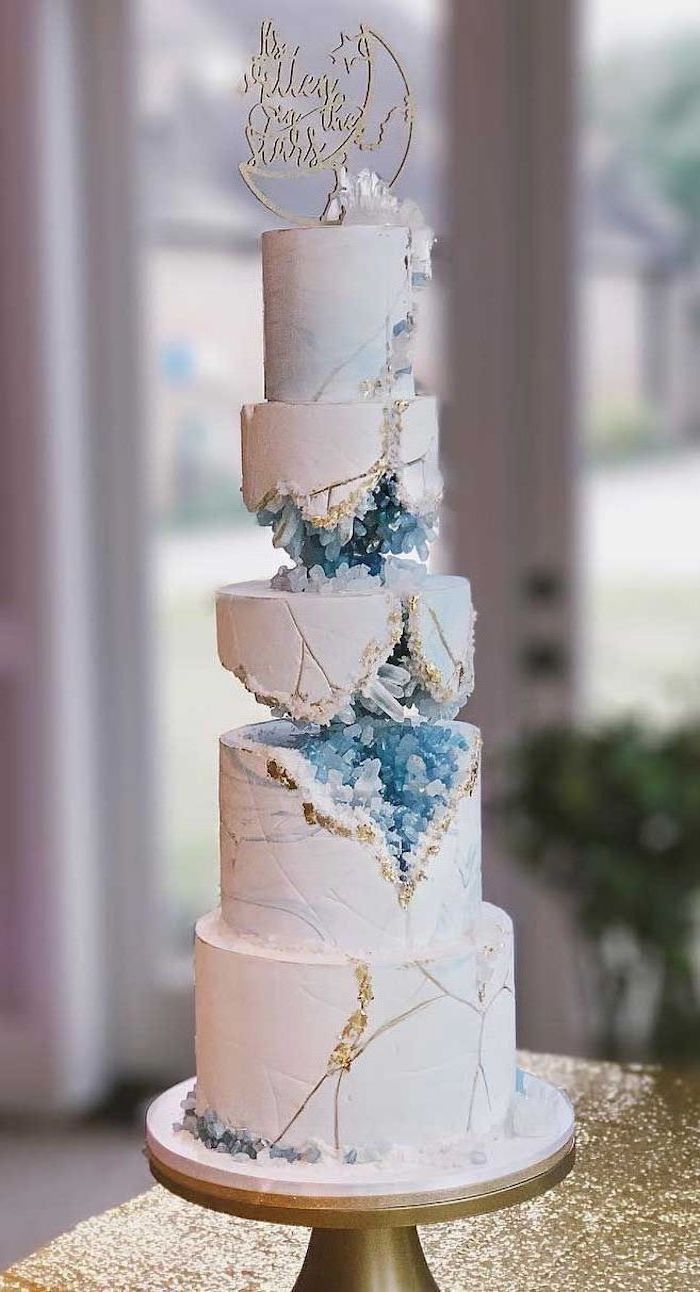 a three tiered wedding cake with blue and white frosting