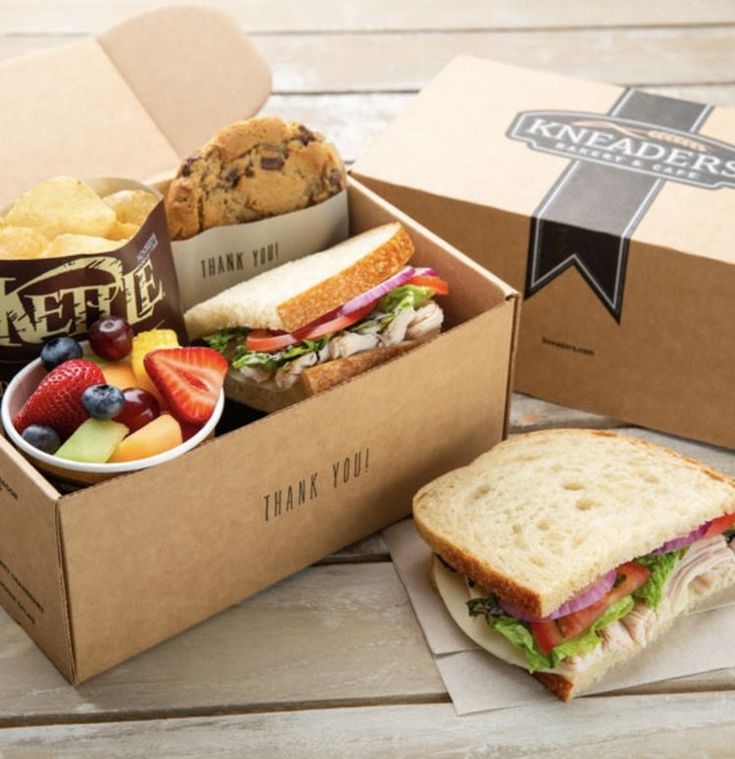 a sandwich box filled with fruit, muffins and other snacks on top of a wooden table