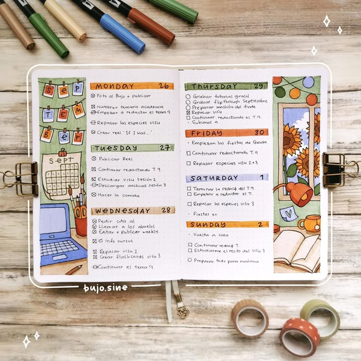 an open planner with markers and scissors next to it on a wooden table, surrounded by crayons