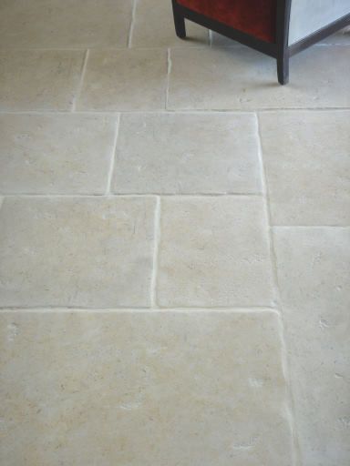 a white tile floor with a wooden chair in the background