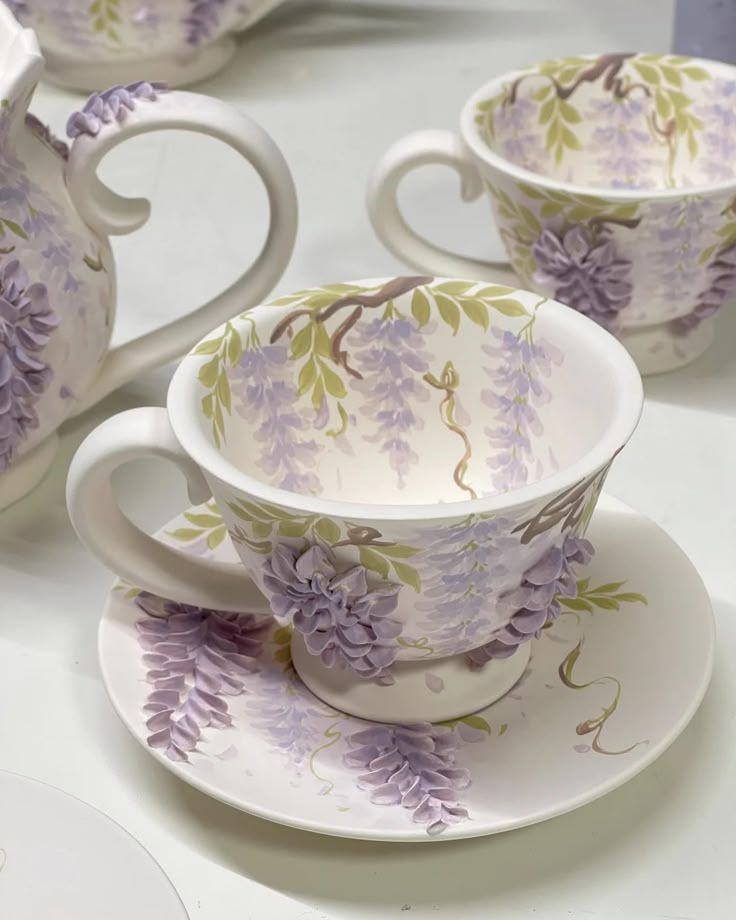 purple flowers are painted on the cups and saucers