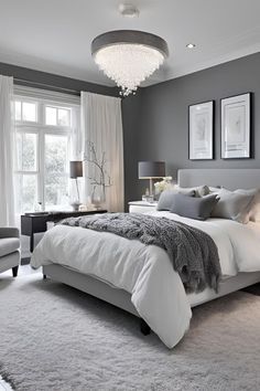 a bedroom with gray walls and white bedding, two chairs and a chandelier