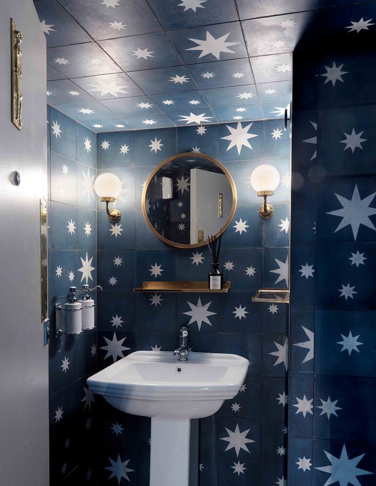 a bathroom with blue and white stars on the wall next to a sink, mirror and toilet