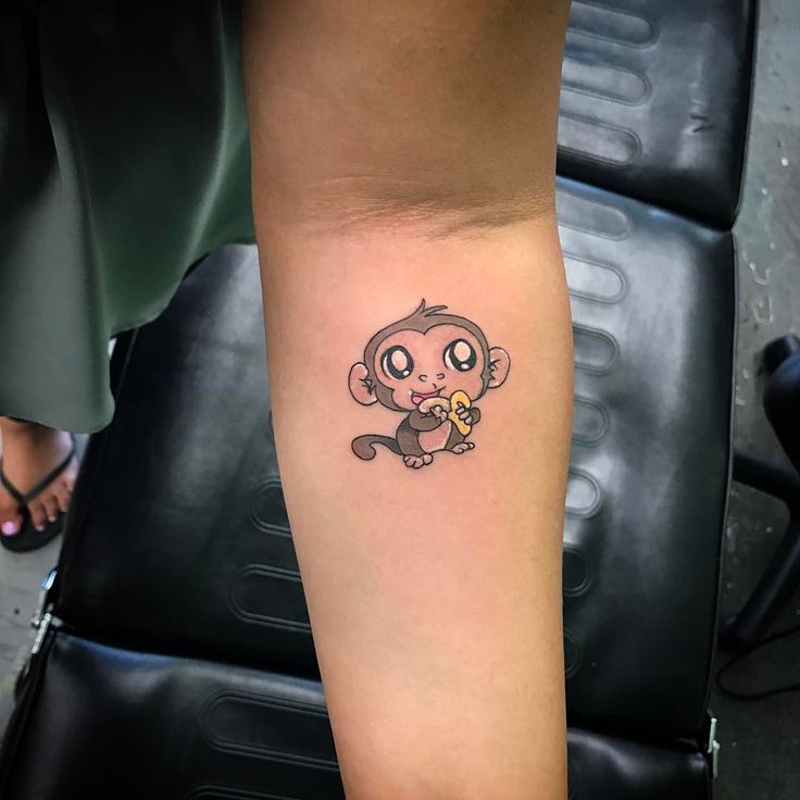 a small tattoo on the arm of a girl with a monkey holding a flower in her hand