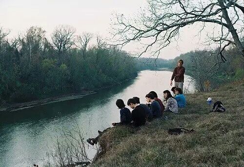 a group of people sitting on the side of a river