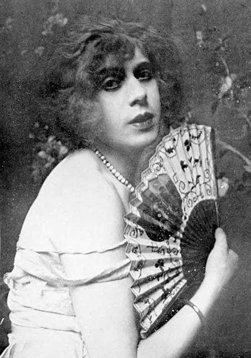 an old black and white photo of a woman holding a fan