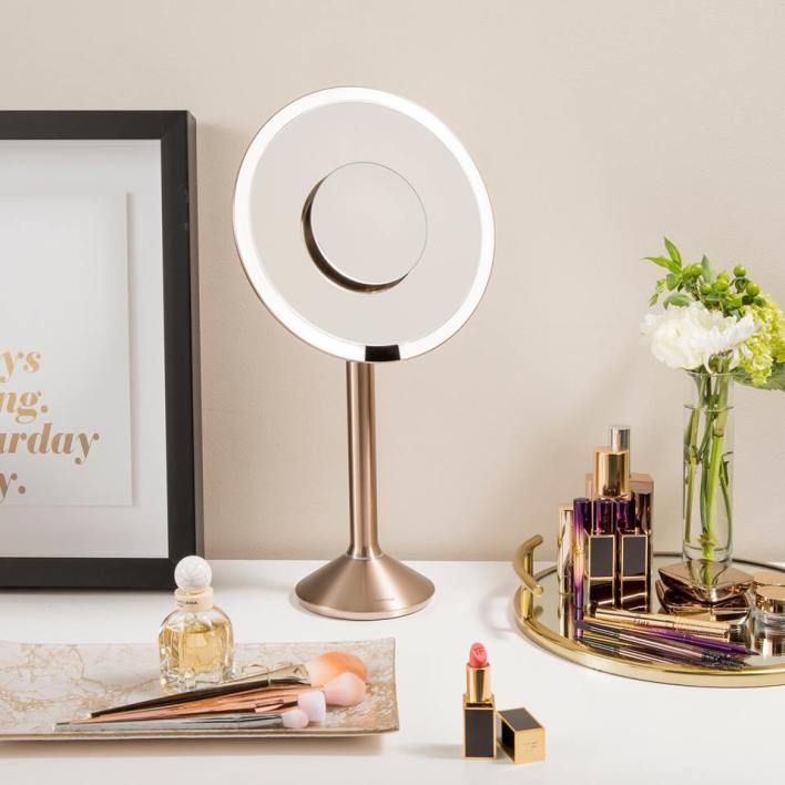 a desk with a mirror, lipstick, and other items on top of the table