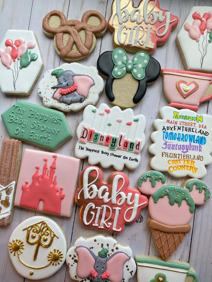 baby girl cookies are arranged on a table with mickey mouse ears and other items in the background