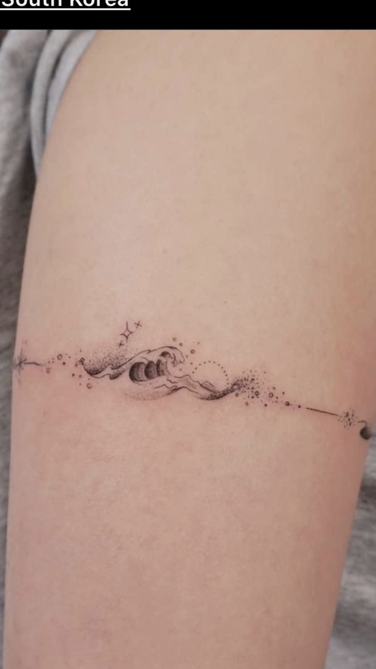 a woman's arm with a small wave tattoo on it