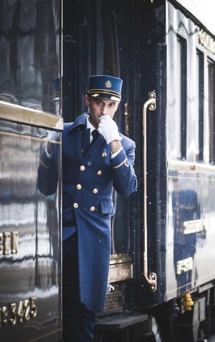 a man in uniform standing on the side of a train