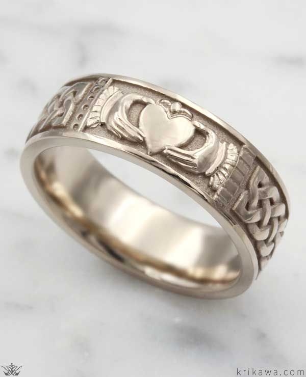 a wedding ring with two hearts in the center on a marble surface, surrounded by celtic symbols