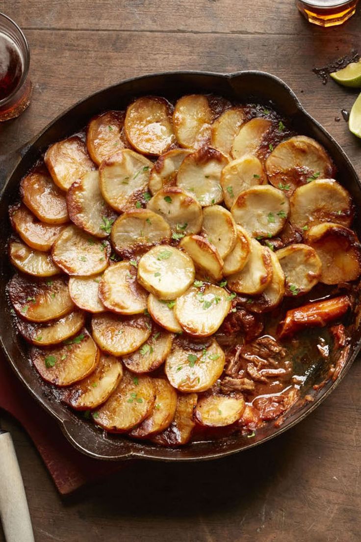 a skillet filled with potatoes on top of a wooden table