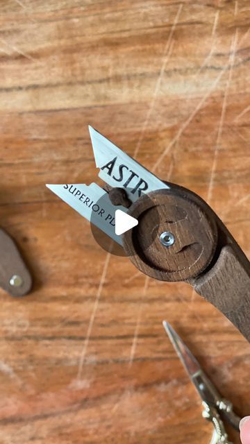 a pair of scissors that are on top of a wooden table with some writing on them