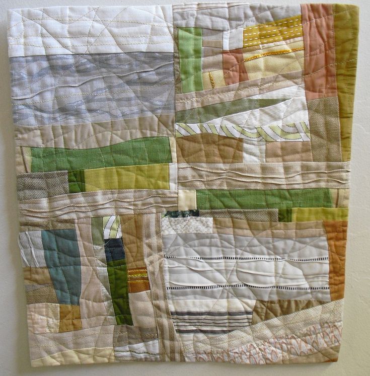 a close up of a quilt on a wall hanging in a room with white walls