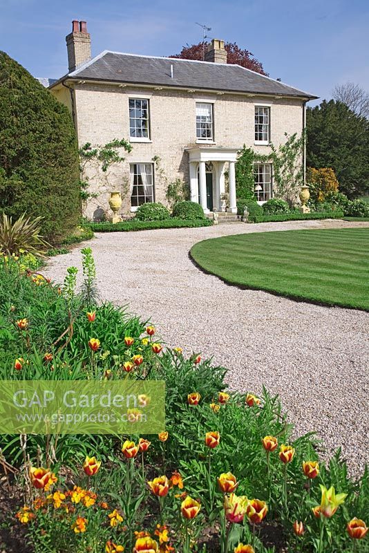 a large house with lots of flowers in the front yard and walkway leading to it