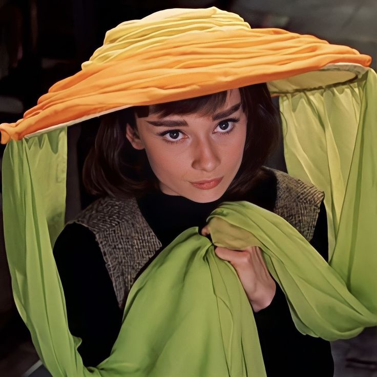 a woman wearing a green and yellow hat with an orange covering over her head,