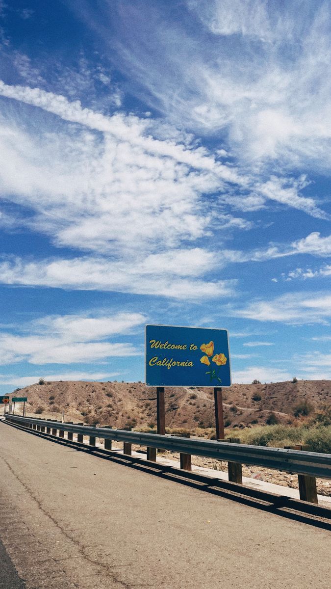 a blue sign sitting on the side of a road in front of a desert landscape