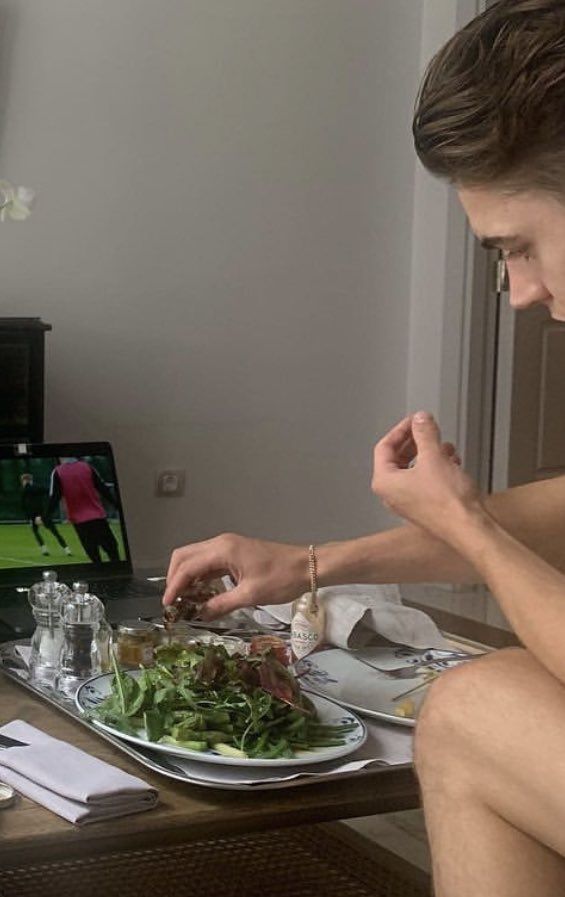 a man sitting at a table with a plate of food in front of his laptop