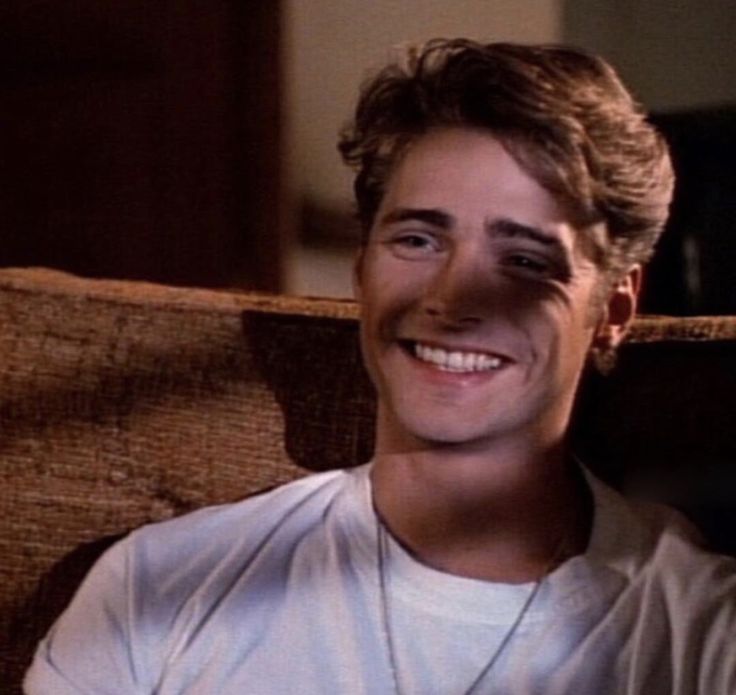 a young man smiling while sitting in a chair