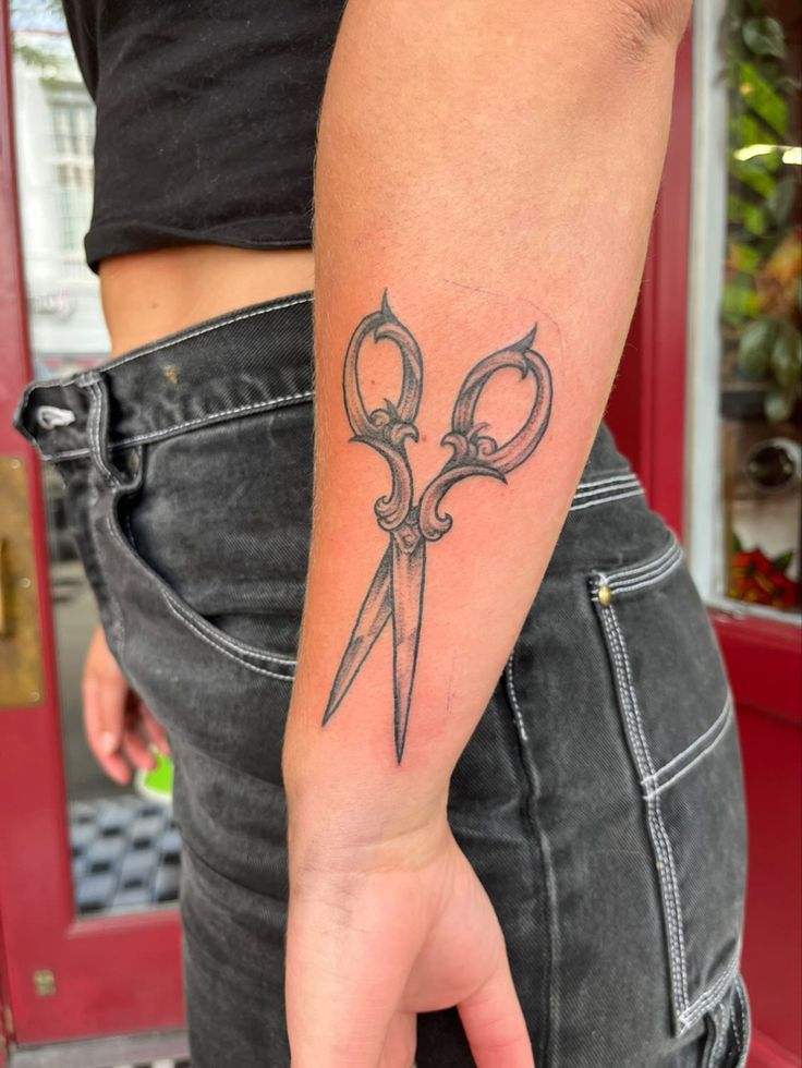 a person with a tattoo on their arm holding a pair of scissor scissors