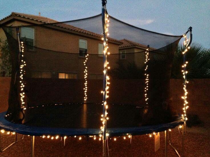 a trampoline covered with lights in front of a house